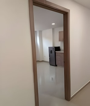 A corridor leading to a kitchen area with a refrigerator and cabinets.