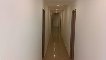 Un pasillo estrecho y bien iluminado con piso reflectante, que conduce a una puerta al final.