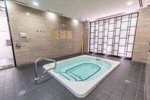 Une piscine intérieure moderne, dotée d’un sol carrelé, d’une échelle métallique et d’un mur orné de panneaux d’avertissement.