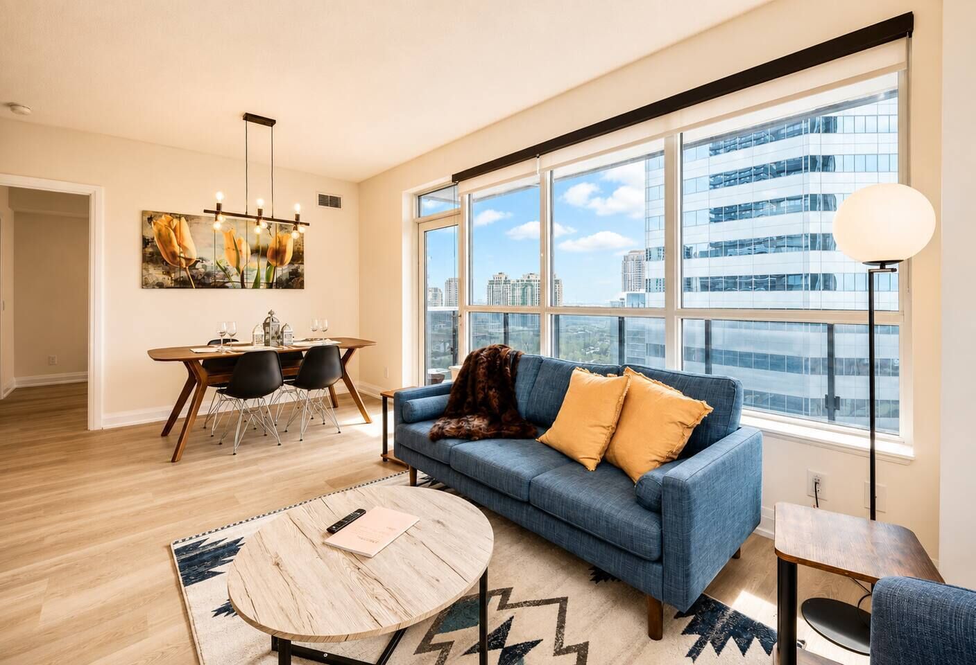 A modern living room with a sofa, a coffee table, and a dining area with chairs and a table.