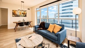 A modern living room with a sofa, a coffee table, and a dining area with chairs and a table.