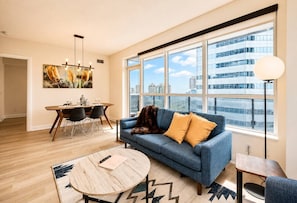 A modern living room with a sofa, a coffee table, and a dining area with chairs and a table.
