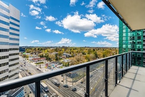 A high-rise building with a view of a cityscape, including roads and a gas station.