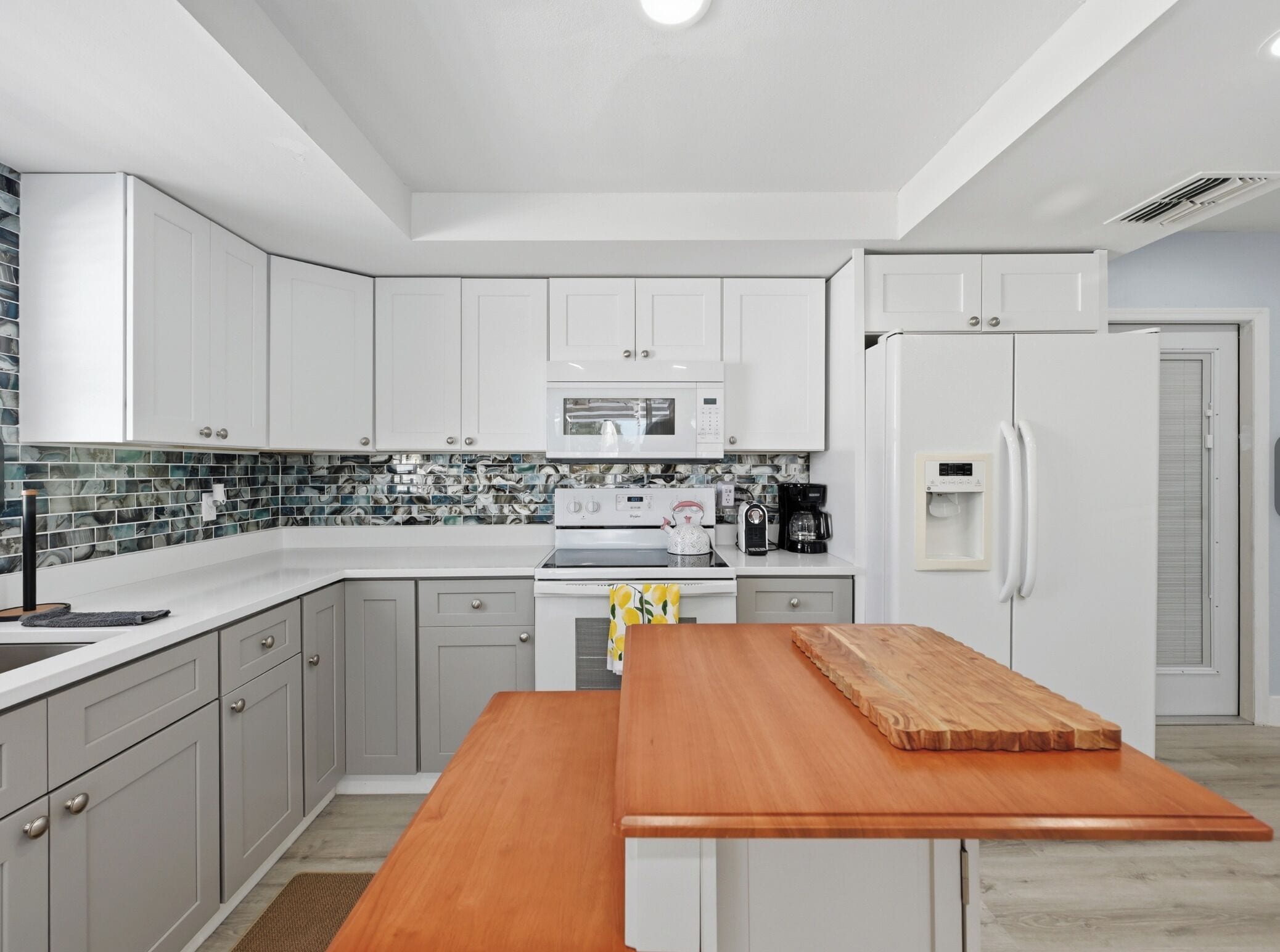A modern kitchen with white cabinets, a microwave, a stove, and a refrigerator.