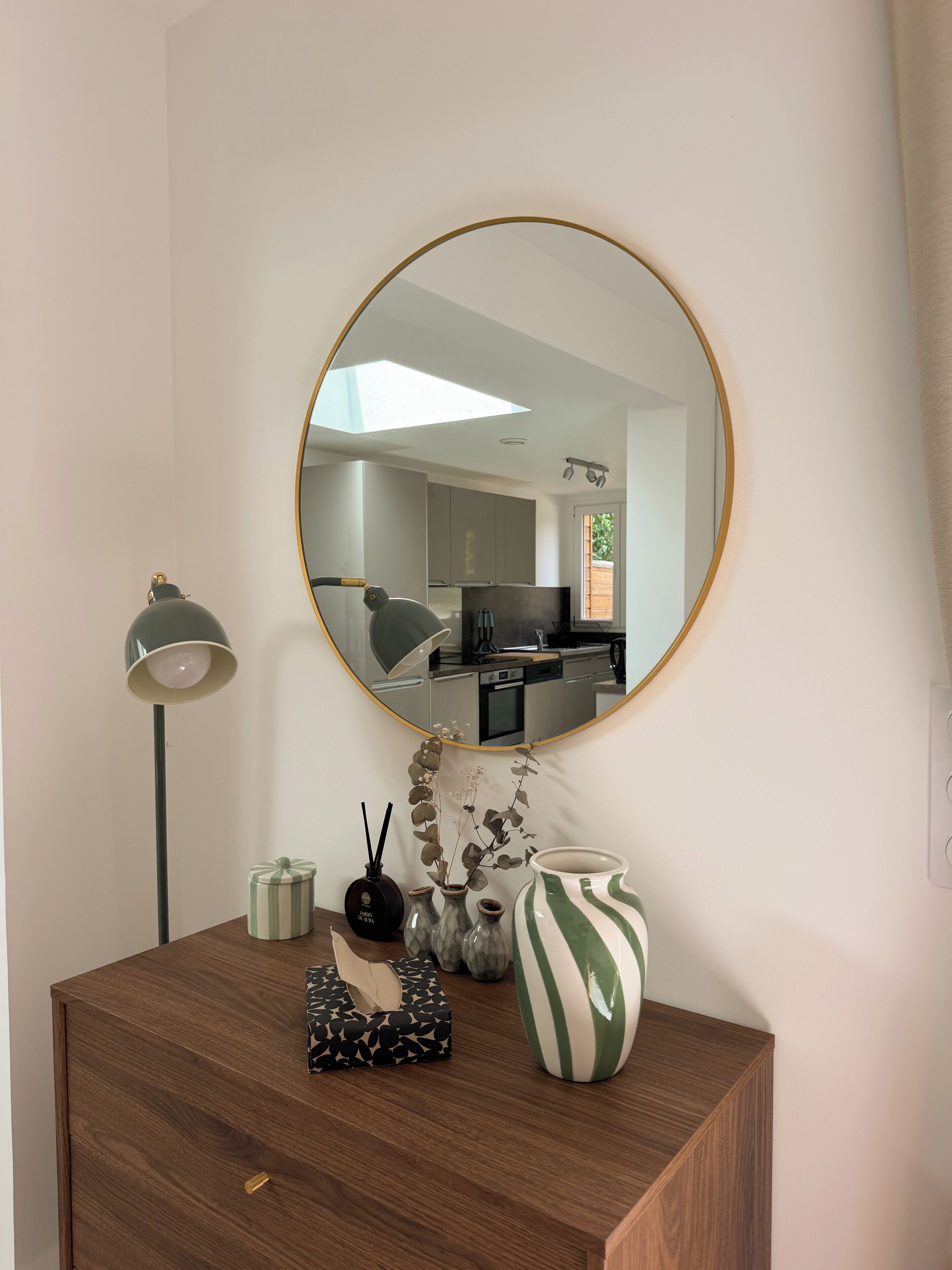 A wooden dresser with a mirror, a floor lamp, and decorative items including vases and a candle holder.