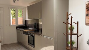 Een moderne keuken met dakraam, roestvrijstalen apparatuur en een plantenstandaard van hout.