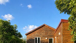 Een houten huis met een stenen muur en een barbecue in de tuin.