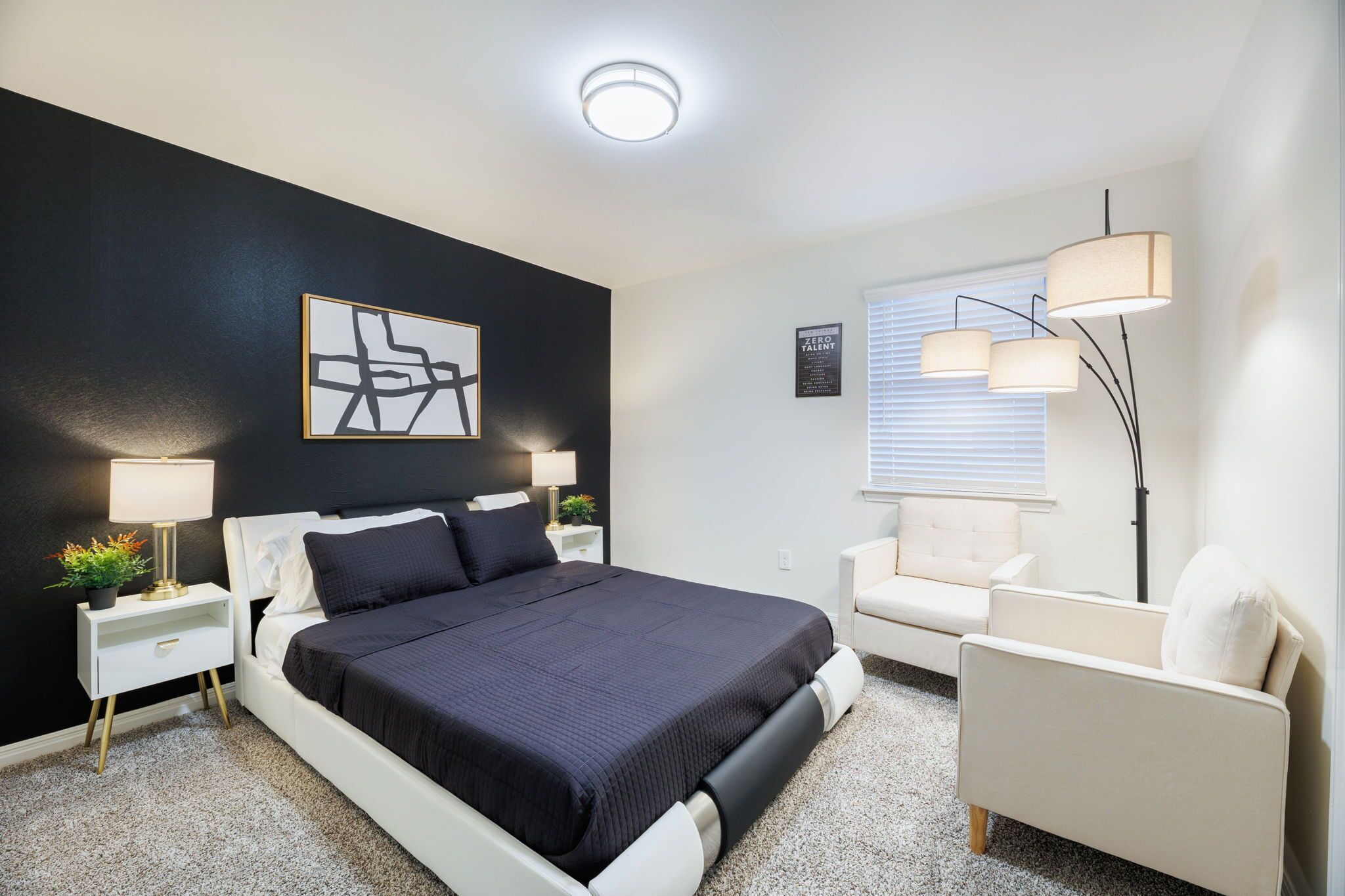 Een moderne slaapkamer met een bed, nachtkastjes, een fauteuil, een vloerlamp en een schilderij aan de muur.