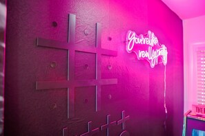 Eine Wand mit einem neonbeleuchteten Schild, das ‚You're really pretty‘ zeigt, und einer kreuzförmigen Metalldeoration.