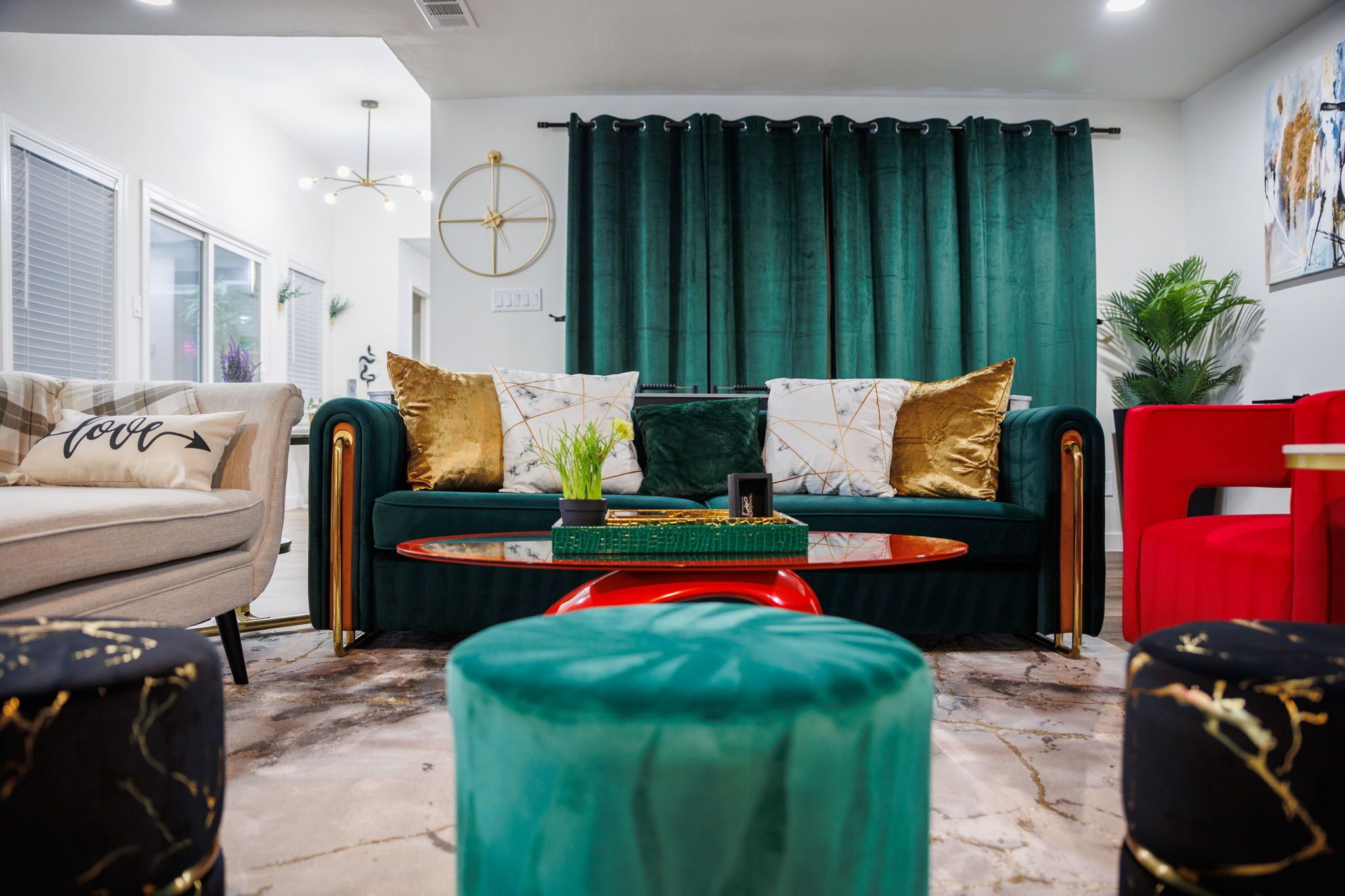 Un saló modern amb un sofà color turquesa, una cadira vermella i una taula de centre amb objectes decoratius.
