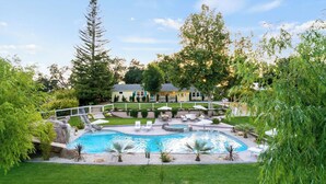 En have med swimmingpool, liggestole og et hus.