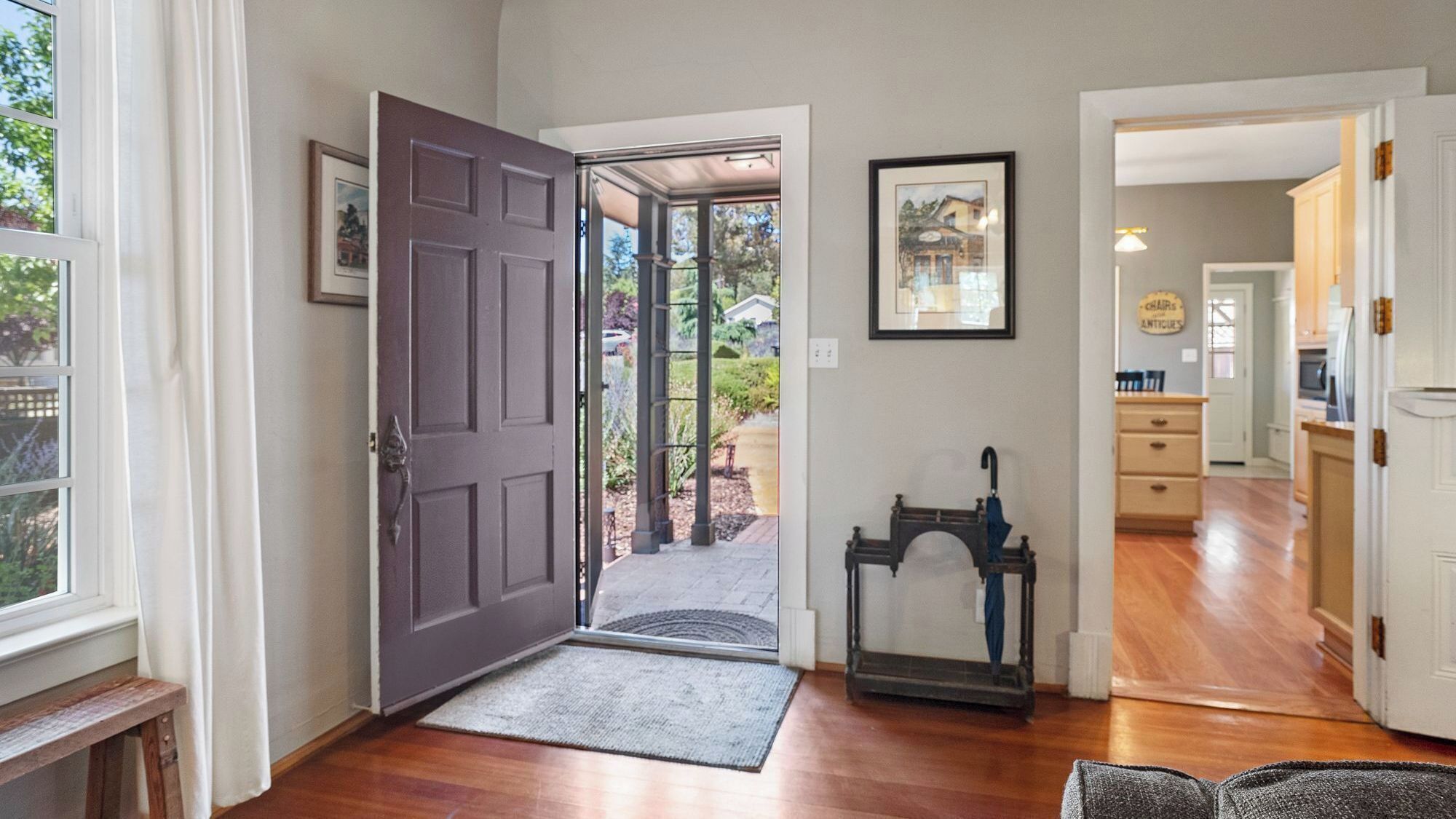 A hallway with a wooden floor, a closed door, a small rug, and a framed picture on the wall.