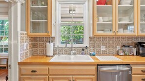 A kitchen with a wooden countertop, a stainless steel sink, and a dishwasher. There are cabinets with glass doors above the countertop. - Ridgeview Retreat by Avantstay Bocce Court + BBQ + Oak Views Paso Robles Wine Country (Paso Robles)