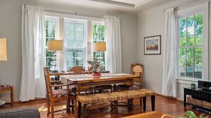 A dining room with a wooden table, chairs, and a bench. There are two windows with curtains, a lamp, and a framed picture on the wall. - Ridgeview Retreat by Avantstay Bocce Court + BBQ + Oak Views Paso Robles Wine Country (Paso Robles)