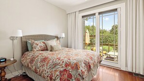 Una camera da letto con un letto grande, un comodino, una lampada e vista sull'esterno tramite una porta scorrevole.