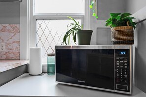 A kitchen with a microwave, a potted plant, and a glass jar. - Rocky Mt Retreat | 2 King Beds | Bike Storage (Kellogg)