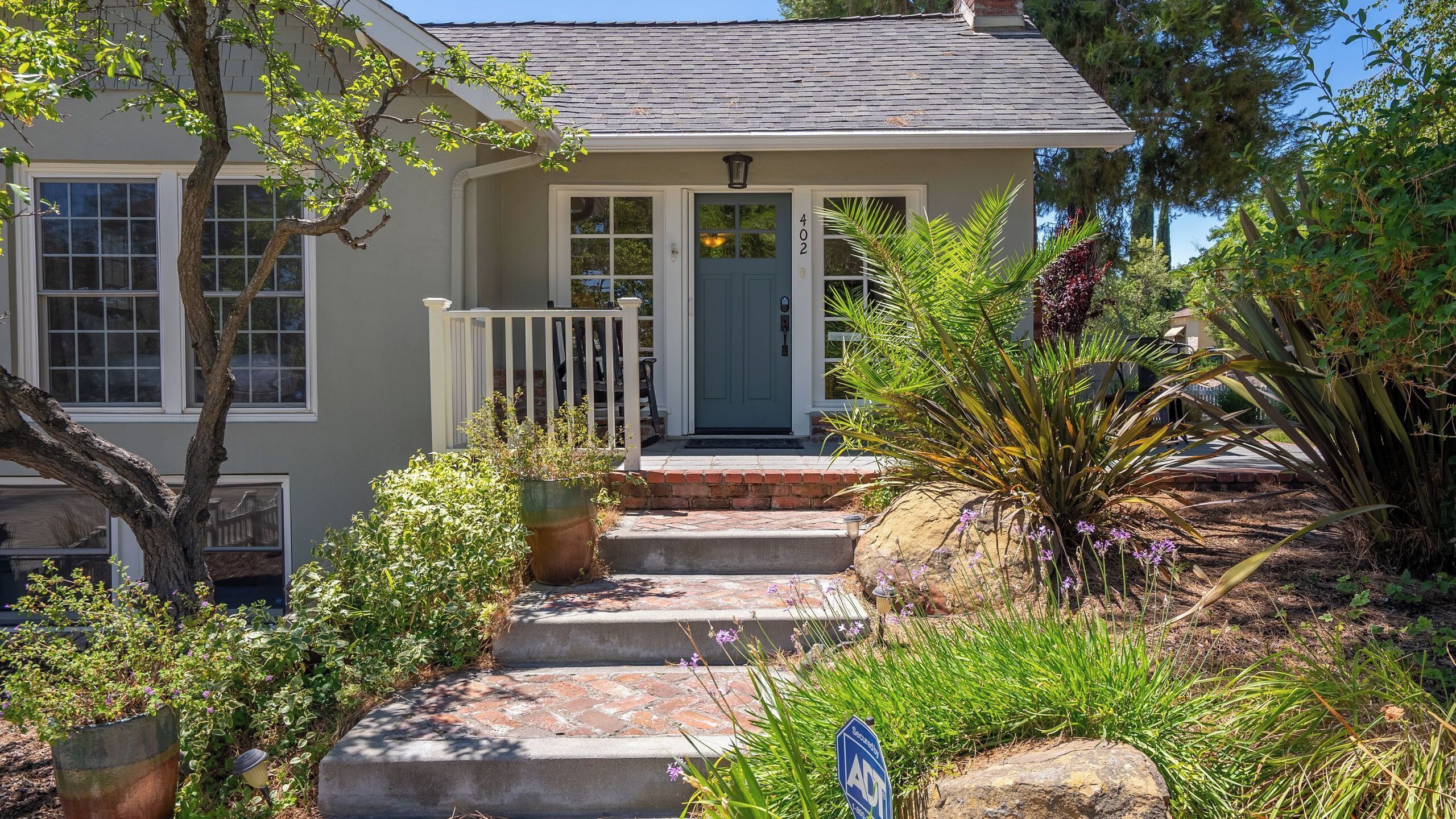 A two-story house with a front porch, a blue door, and a mailbox.