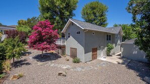A single-story house with a stone pathway leading to the entrance, surrounded by trees and a small garden. - Chateau Paso by Avantstay Pool Table + Private Deck Walk to Downtown Paso (Paso Robles)