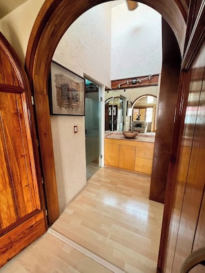 A hallway leading to a kitchen with wooden cabinets and a large mirror.