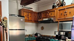 Uma cozinha com armários de madeira, geladeira de aço inoxidável, fogão preto e painel de azulejos.