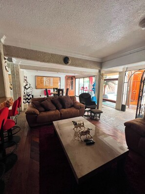 A spacious living area with a brown sofa, red chairs, and a coffee table with figurines.