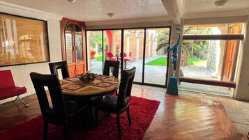 Un comedor con una mesa redonda, sillas y una alfombra roja.