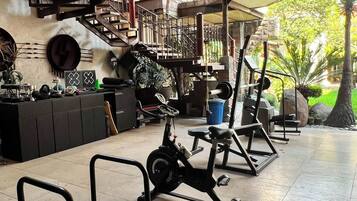 Un gimnasio con equipo de ejercicio, una escalera y vistas a zonas verdes.