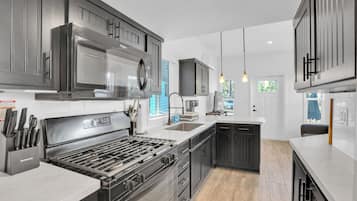 A modern kitchen with stainless steel appliances, a central island, and a view of the outdoors.