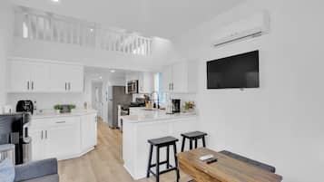 A modern kitchen with white cabinetry, a central island, and a dining area with a wooden table and bar stools.