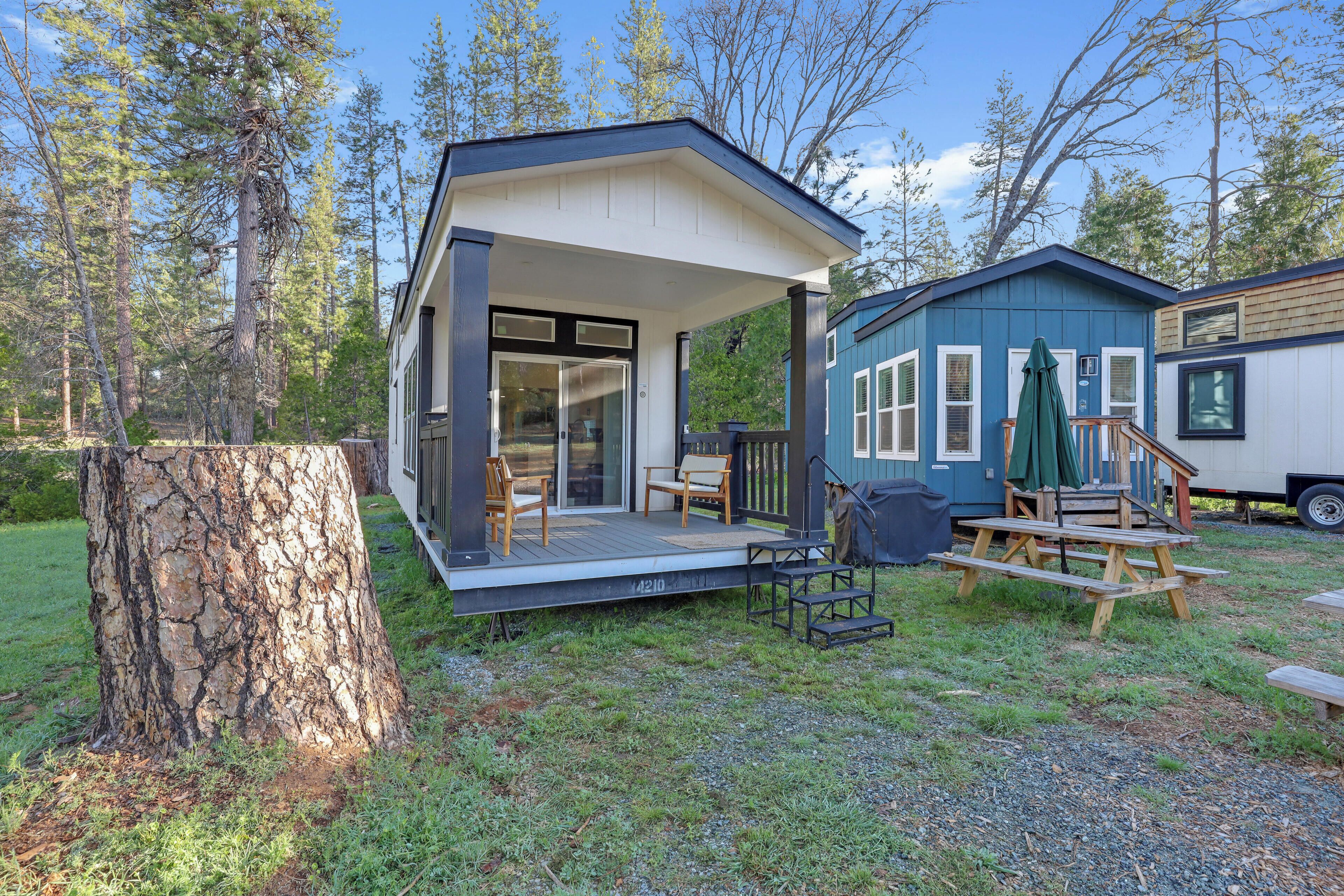 A cabin with a porch, a deck, and a small outdoor seating area.