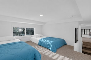A bedroom with two beds, a window with blinds, a staircase, and a ceiling light.