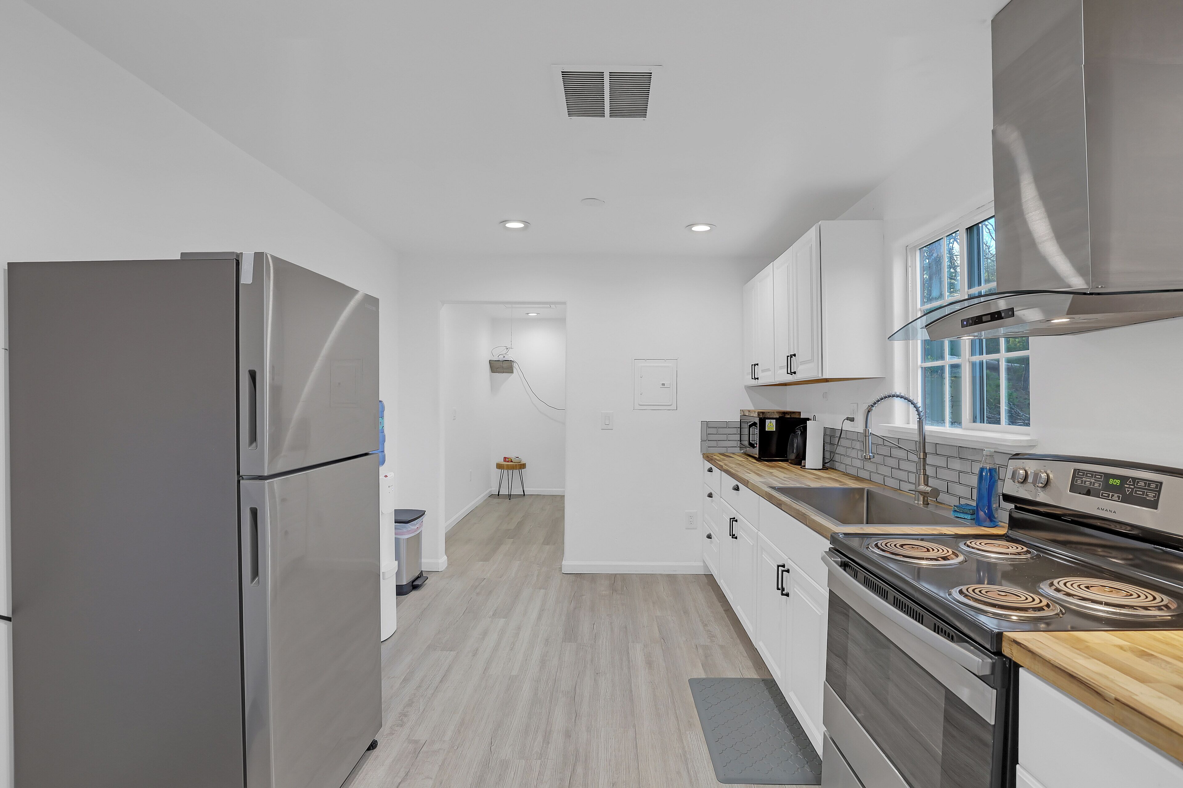 A modern kitchen with stainless steel appliances, a wooden countertop, and a view to the outside.