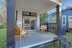A covered outdoor area with a wooden deck, two wooden chairs, and a bench.