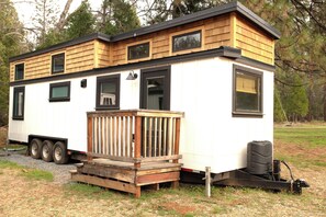 A mobile home with a deck, a small porch, and a sliding door. - Tiny House Village (Groveland)