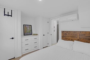 Quarto com uma cama, penteadeira, quadro emoldurado e cabeceira de madeira.