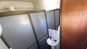 Un baño pequeño con un lavamanos blanco, un espejo y una puerta de madera.