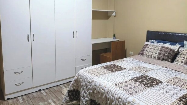 Un dormitorio con cama, armario y mesita de noche.