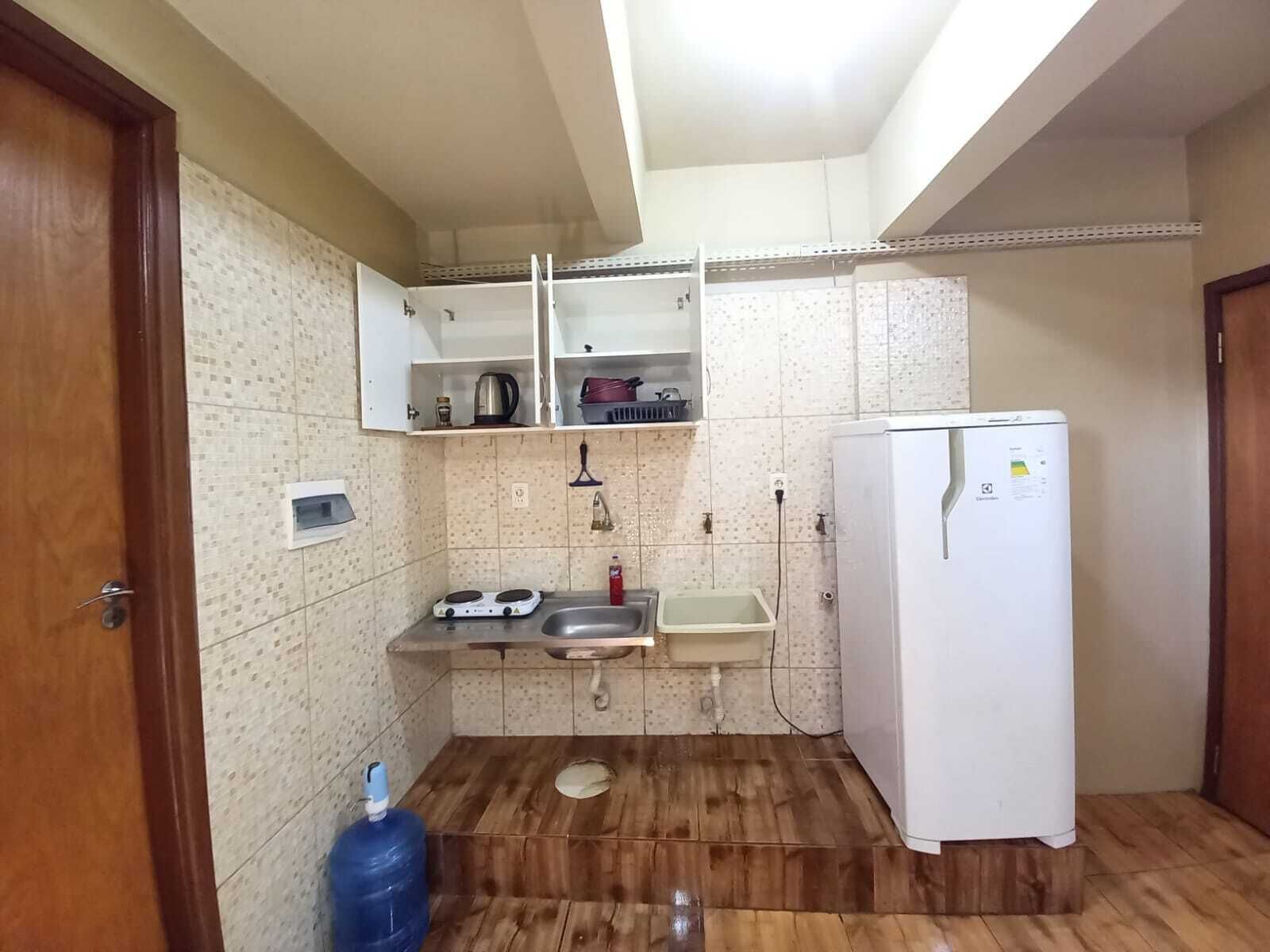 Eine kleine Küche mit Spüle, Herd, Kühlschrank und Wasserspender.
