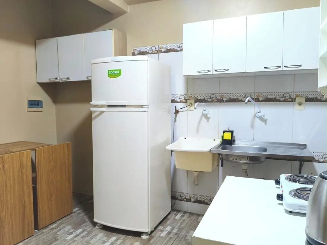Cocina compacta con refrigerador, lavamanos, estufa y alacenas.