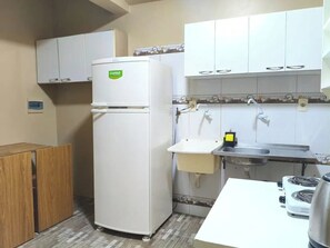 Uma cozinha compacta com geladeira, pia, fogão e armários.