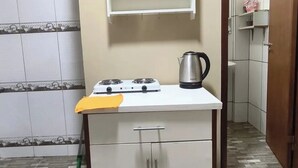 Una cocina con estufa a gas, un hervidor y un estante sobre la encimera.