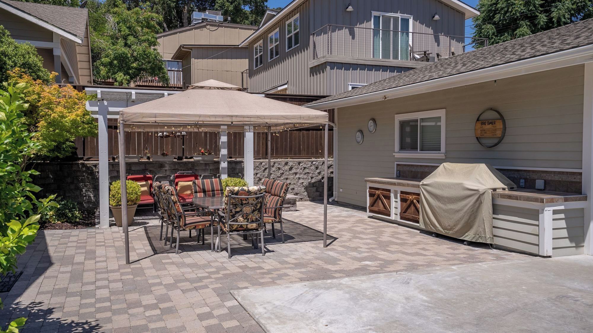 Une terrasse dotée d’un espace repas couvert, de sièges d’extérieur et d’un coin barbecue.