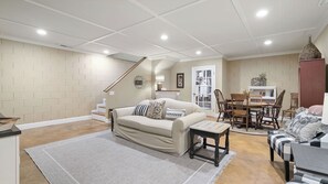 Un salon avec un canapé, une table à manger et des chaises. Un escalier mène à un autre niveau.