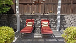Two lounge chairs with cushions, a stone wall, and a wooden fence in the background. - 13th Street Retreat by Avantstay Ensuite Suites + Sun Porch & Patio Downtown Paso Robles (Paso Robles)