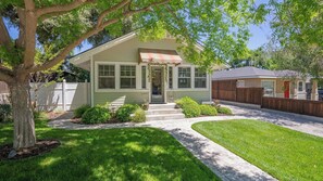 Une maison de plain-pied avec un porche à l’avant, un petit jardin et une allée menant au garage.