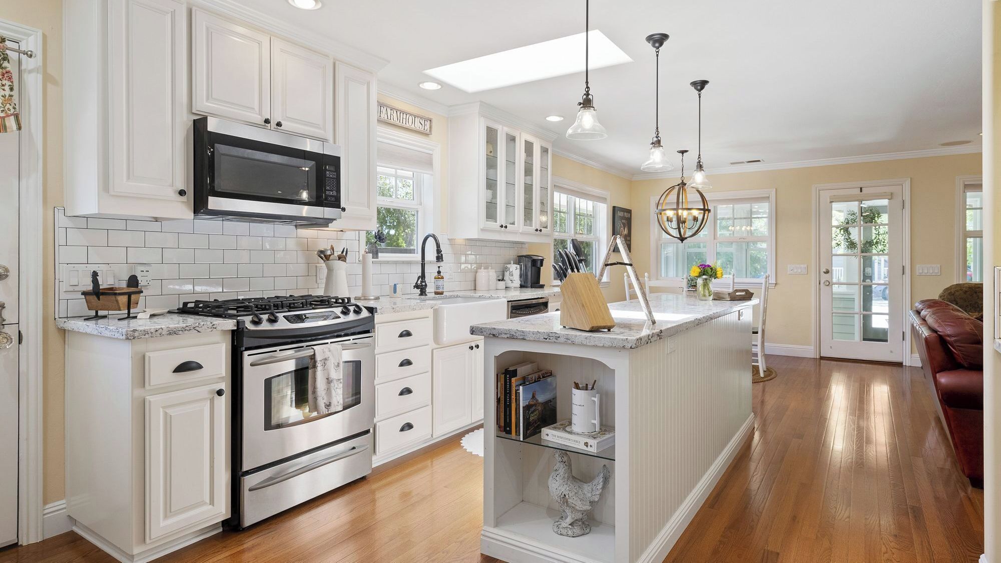 A kitchen with white cabinetry, stainless steel appliances, and a central island with a glass top.