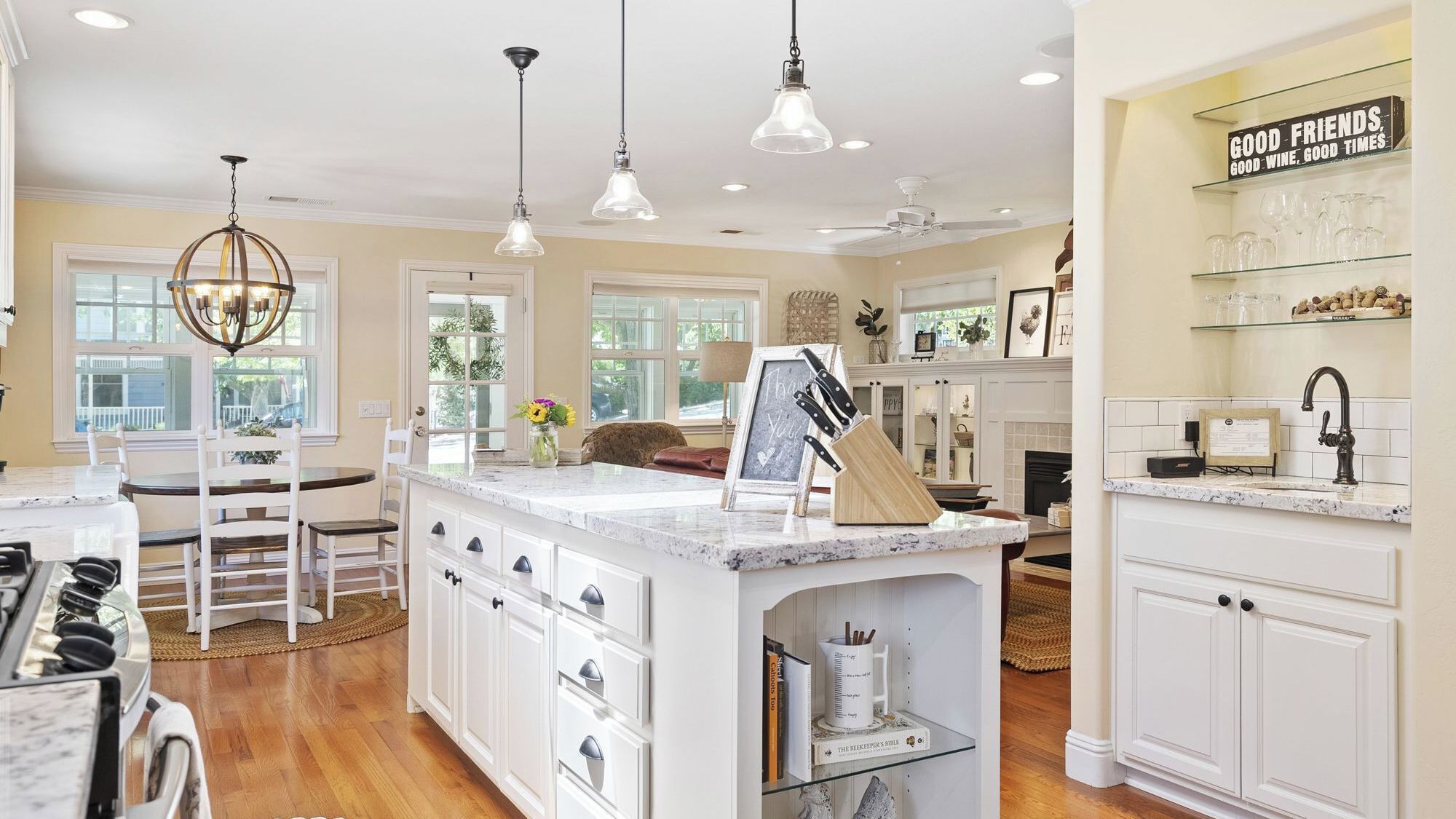 A spacious kitchen with white cabinetry, a marble countertop, and pendant lighting.