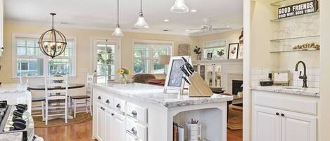 A spacious kitchen with white cabinetry, a marble countertop, and pendant lighting.