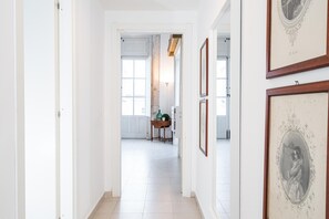 Ein Korridor mit weißen Wänden, gefliestem Boden und gerahmten Bildern an der Wand.
