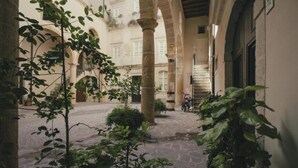 Un patio interior con suelo de piedra, columnas y plantas en macetas.